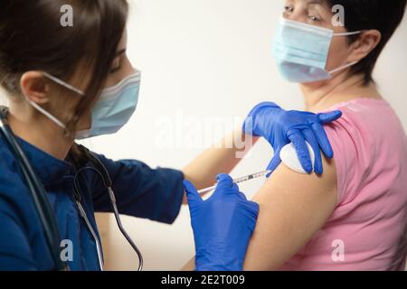 Health. Close up doctor or nurse giving vaccine to patient using the syringe injected. Works in face mask. Protection against coronavirus, COVID-19 pandemic and pneumonia. Healthcare, medicine. Stock Photo