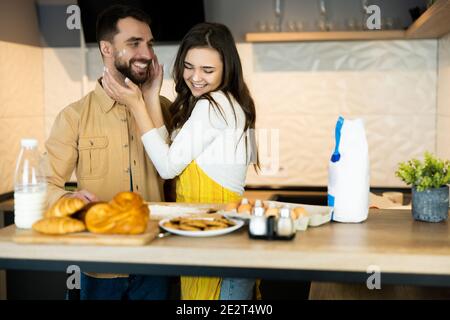 Lovely couple is having fun and hugging each other while cooking. They look happy being together in the kitchen together. They are baking some cookies Stock Photo