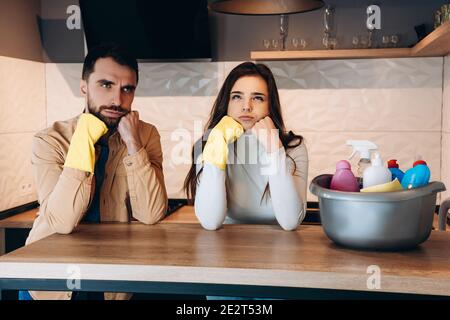 Wondering couple doing house cleaning in modern kitchen at home.Photo of young man and pretty woman washing with detergent and with wife. Stock Photo