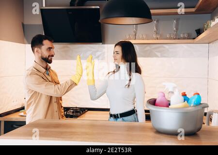 Young couple is giving high five after cleaning in kitchen. Happy couple finished cleaning kitchen together Stock Photo