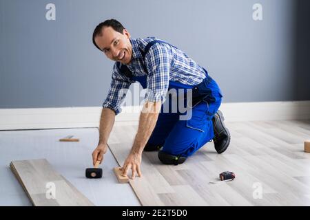 Hardwood Floor Renovation. Construction Worker Doing New Laminate Installation Stock Photo