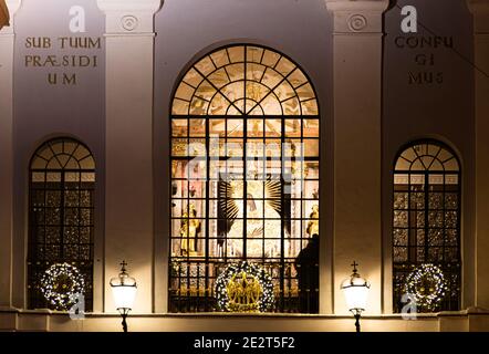 The Gate of Dawn or Aurora in Vilnius, the chapel of Our Lady of the Gate of Dawn is in the middle behind the glass window, night view with snow Stock Photo
