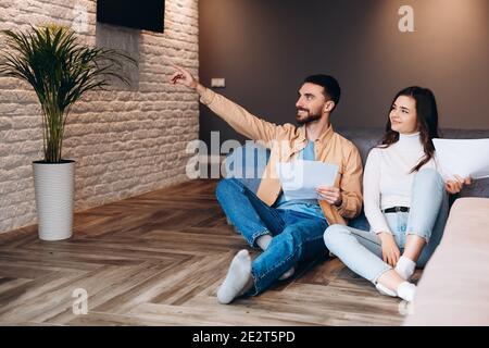 Couple examining documents. Cheerful young couple examining documents while sitting close to each other on the floor at their new apartment Stock Photo