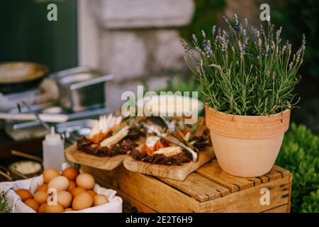 Lavender in a flower pot on a wooden box with cutting boards with cold cuts and chicken eggs in a box. Stock Photo