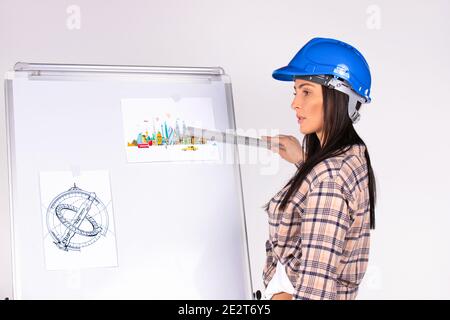 Serious young female engineer presents her plan and shows a diagram with a ruler. White background. Stock Photo