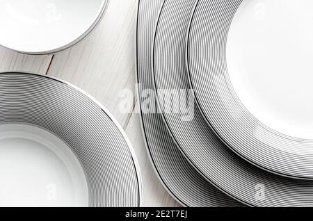 White round classical porcelain plates with a gray pattern stand on a white wooden table Stock Photo