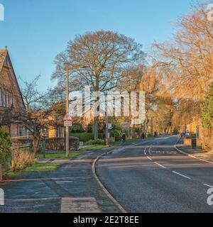 A road through a Yorkshire village. A chapel stands to one side as the road bends into the distance. Trees are are on each side. Stock Photo