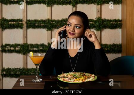 Portrait of a pretty woman conversing on the phone while sitting in a restaurant. Stock Photo