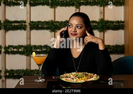 Portrait of a pretty woman conversing on the phone while sitting in a restaurant. Stock Photo