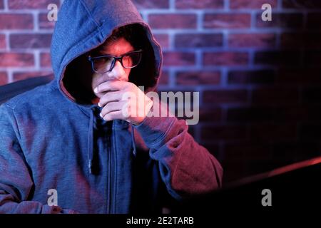 hooded man working on laptop stealing personal data  Stock Photo