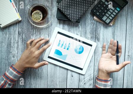 man's hand working on digital tablet at office desk, using self created chart  Stock Photo