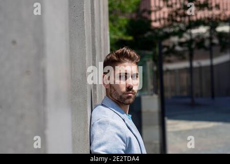 Bearded man leaning against wall and thinking Stock Photo
