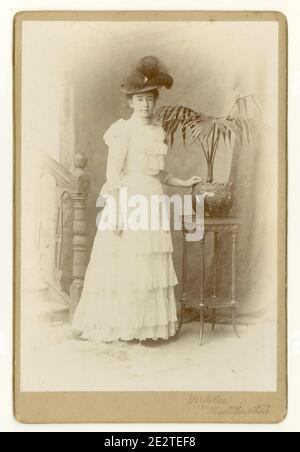 Late Victorian or early Edwardian era cabinet card of pretty young woman in white summer dress, high necked collar, hat with feathers, Hemel Hempstead, Hertfordshire, U.K. circa 1900, 1901