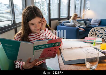 Homeschooling, during the January 2021 lockdown, children studying at home for school, their mother in the home office working on the laptop with vide Stock Photo