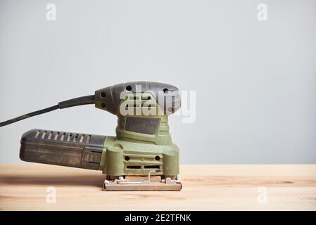 Electric sander on a pine wood plank, carpentry tool. Image with copy space. Stock Photo