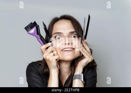 emotional woman presses hairdressing tools to her face. beauty salon concept Stock Photo