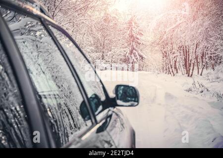 Gray car on the winter road through the beautiful, fabulous, snow-covered forest with the sun. Side view Stock Photo