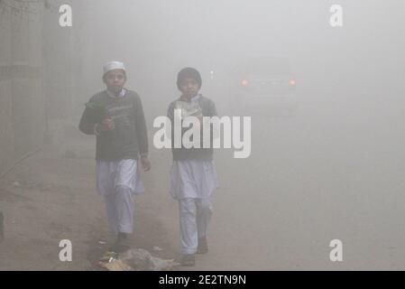 Lahore, Pakistan. 15th Jan 2021. Pakistani Commuters and people make their way amid dense fog on a cold winter morning in Lahore. The intensity of the fog, visibility was reduced to zero, making it difficult for vehicles to maneuver on the roads. The traffic police have issued safety guidelines for people after the fog rolled into the city. the visibility must reduce to less than 1 kilometre, the humidity levels must be more than 90 per cent, the air must be still and the sky clear. Only then are there chances for fog. (Photo by Rana Sajid Hussain/Pacific Press/Sipa USA) Credit: Sipa USA/Alamy Stock Photo