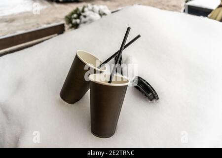 Two paper cups with coffee keep warm on a scarf in the snow, winter love tale Stock Photo
