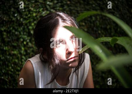 Young girl hiding behind plants Stock Photo