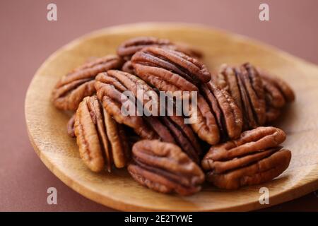 Pecan nut close-up in spoon on brown background.Healthy fats.Heap shelled Pecans nut closeup. Ingredient of the keto diet.Tasty raw organic food and Stock Photo