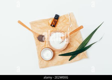 Spa set with bowl of sea salt, natural black clay, nourishing cream and bottle of essential oil on white table, top view. Stock Photo