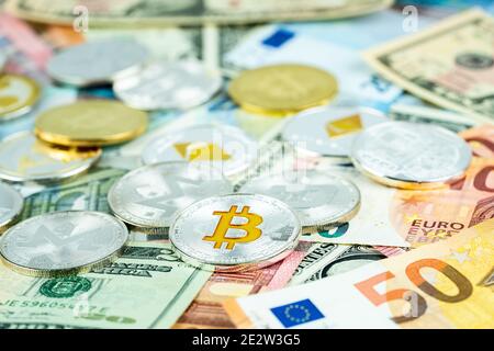 Various cryptocurrency coins on paper dollar and euro banknotes. Bitcoin, ethereum, litecoin and others modern virtual currency. Digital crypto. Metal Stock Photo