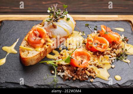Bruschetta with salmon, poached egg and dye rice. on a wooden board