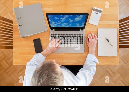 Businessman working from home with laptop, smartphone and calculator - view from above - focus on the keyboard Stock Photo