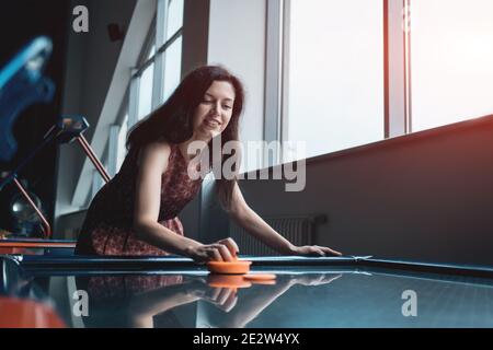 beautiful brunette female playing air hockey with friend Stock Photo