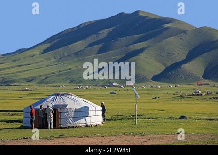 Mongols / Mongolian men at traditional ger / yurt equipped with solar panels on the steppe of Mongolia in summer Stock Photo