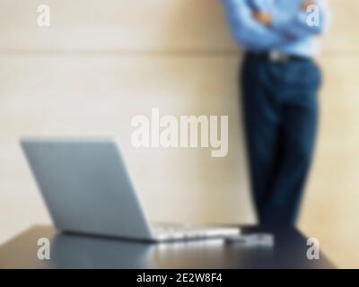 Midsection of businessman with laptop and cell phone on desk in foreground Stock Photo