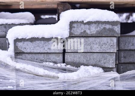 Gray bricks stacked laminated and covered with snow street view Stock Photo