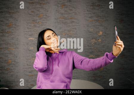 Cheerful young brunette woman takes selfie using smartphone Stock Photo