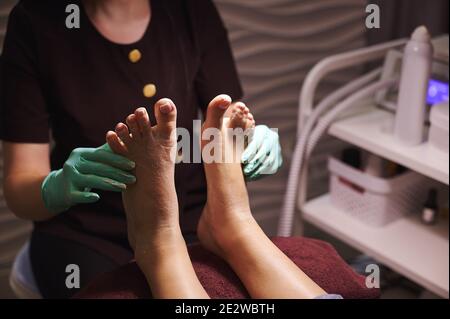 Pedicurist gently massaging woman legs after pedicure Stock Photo