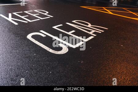 Keep Clear written on the wet asphalt road Stock Photo