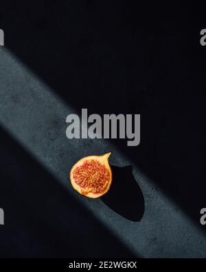 Minimal photo of a fig half on dark background in a ray of light Stock Photo
