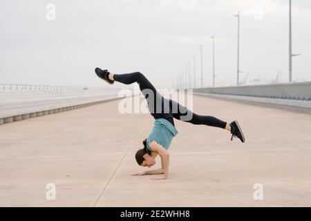 sporty girl doing a handstand while dancing in the street Stock Photo