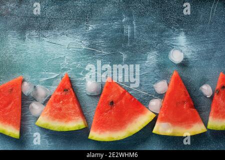 Slices of fresh watermelon with ice on a blue concrete background. Detox and vegetarian concept. Top view, copy space, banner Stock Photo