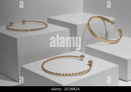 Three modern Golden bracelets on white geometric background Stock Photo