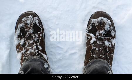 Male legs in snow-covered winter boots, top view. Winter walk in the snow. Focus on your legs. Beautiful white winter weather with fresh snowfall Stock Photo