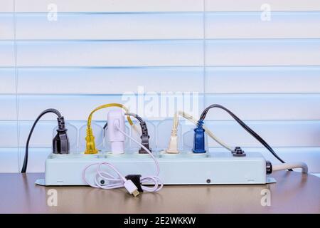 Horizontal shot of a full power strip on a desk in front of a Venetian blind background. Stock Photo
