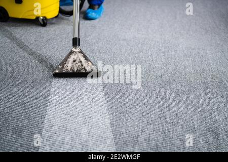 Professional Carpet Cleaning Service. Vacuum Cleaner. Janitor Removing Stain Stock Photo