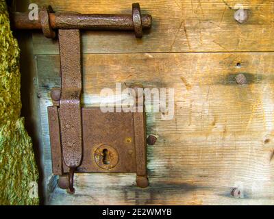 old rusted door fitting with big lock on wooden door Stock Photo