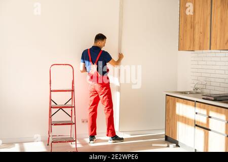 Rear back behind view photo of unrecognizable repairman master using rule to measure the required width of drywall and put label mark Stock Photo