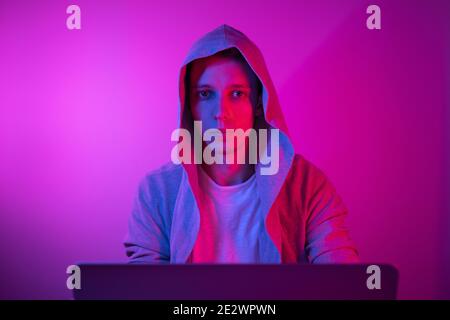 Gamer plays on a laptop. The programmer writes the code. Man on a colored background Stock Photo