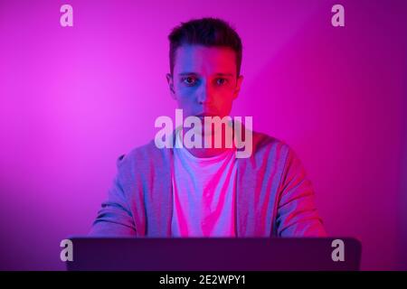 Gamer plays on a laptop. The programmer writes the code. Man on a colored background Stock Photo
