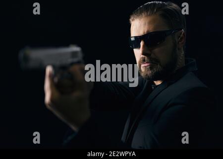 Bearded killer in sunglasses with gun in hands Stock Photo