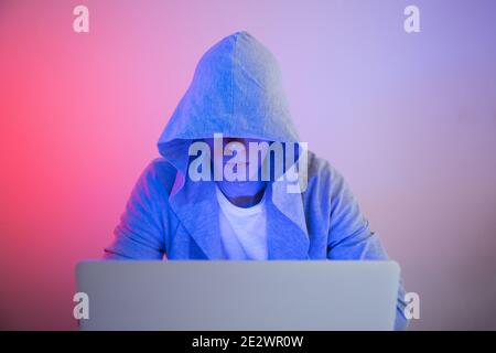 Gamer plays on a laptop. The programmer writes the code. Man on a colored background Stock Photo