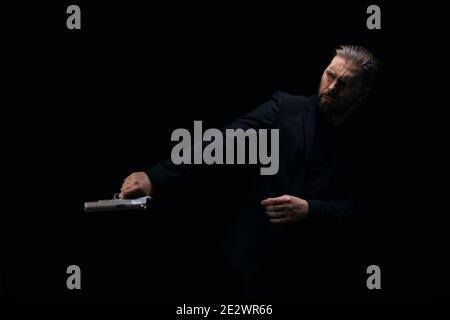 Brutal killer posing in studio with gun in hands Stock Photo